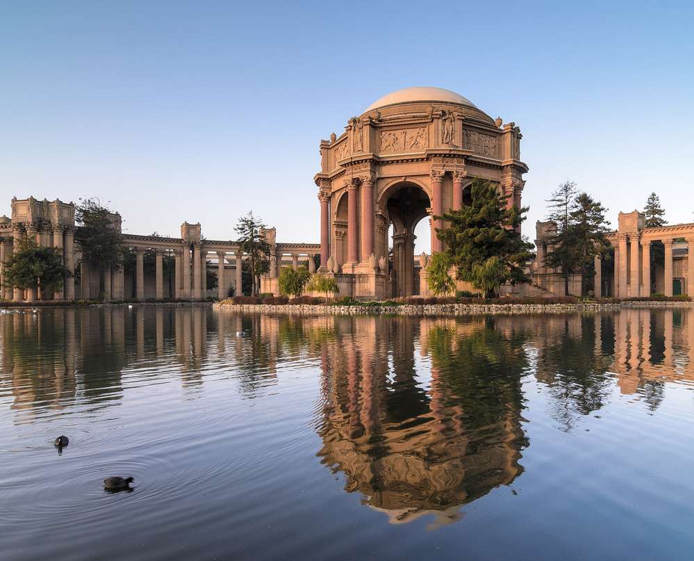 O Palácio de Belas Artes em San Francisco refletido em um lago tranquilo ao entardecer.