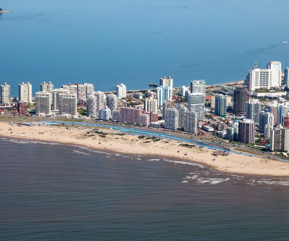 Vista aérea da orla de Punta del Este, com praias de areia dourada e uma vibrante linha de arranha-céus
