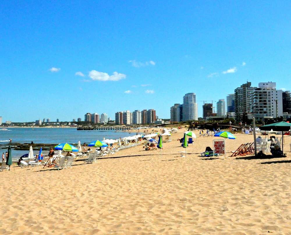 A Playa Mansa em um dia ensolarado, com algumas pessoas na areia.