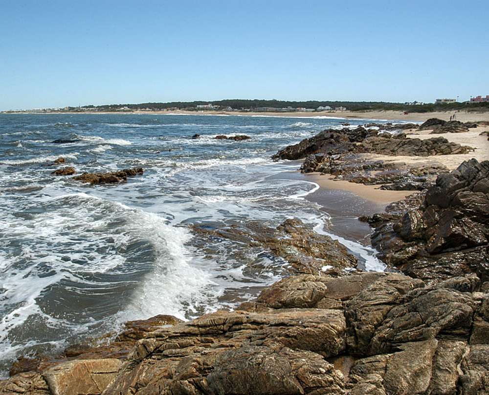 O mar batendo nas pedras da Playa Montoya, durante um dia de sol.