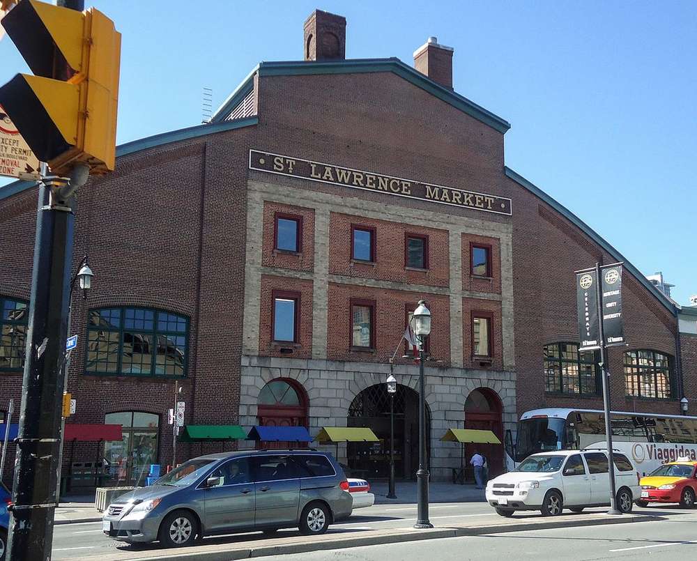 A fachada histórica do St. Lawrence Market, em Toronto, com suas grandes janelas e tijolos vermelhos.