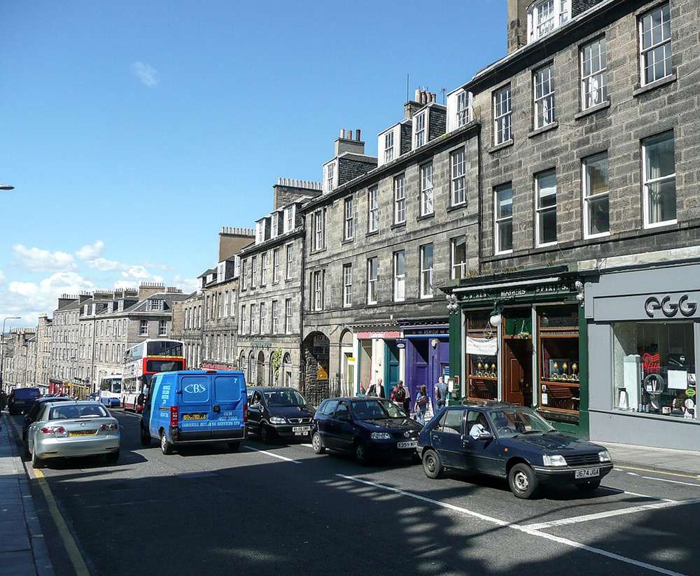 A movimentada Broughton Street, com prédios históricos de pedra e lojas coloridas no Broughton, em Edimburgo, Escócia.