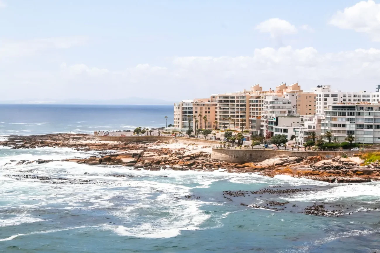 Vista diurna para o mar agitado na região de Sea Point, com alguns edifícios de hotéis à direita.