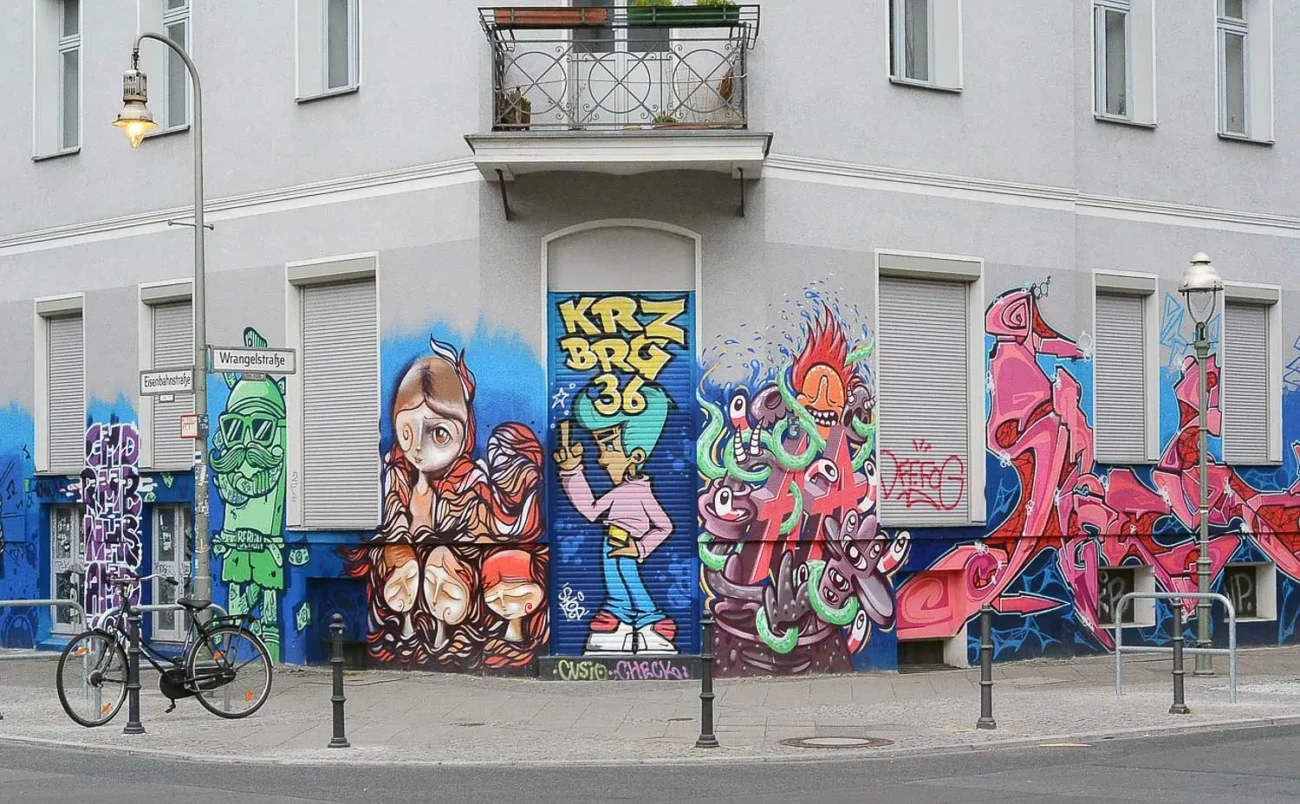 Edifício cinza com vários grafites coloridos na parte inferior da fachada.
