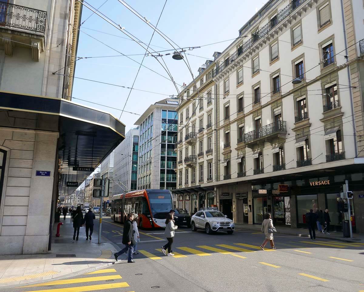 A Rue du Rhône em Rue Basses, uma rua movimentada com lojas de marcas de grife, e um bonde passando no centro de Genebra.