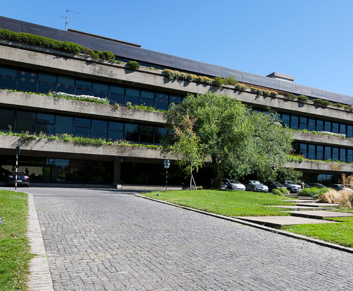 Edifício moderno da Fundação Calouste Gulbenkian em meio a vegetação com gramado e estacionamento ao fundo.
