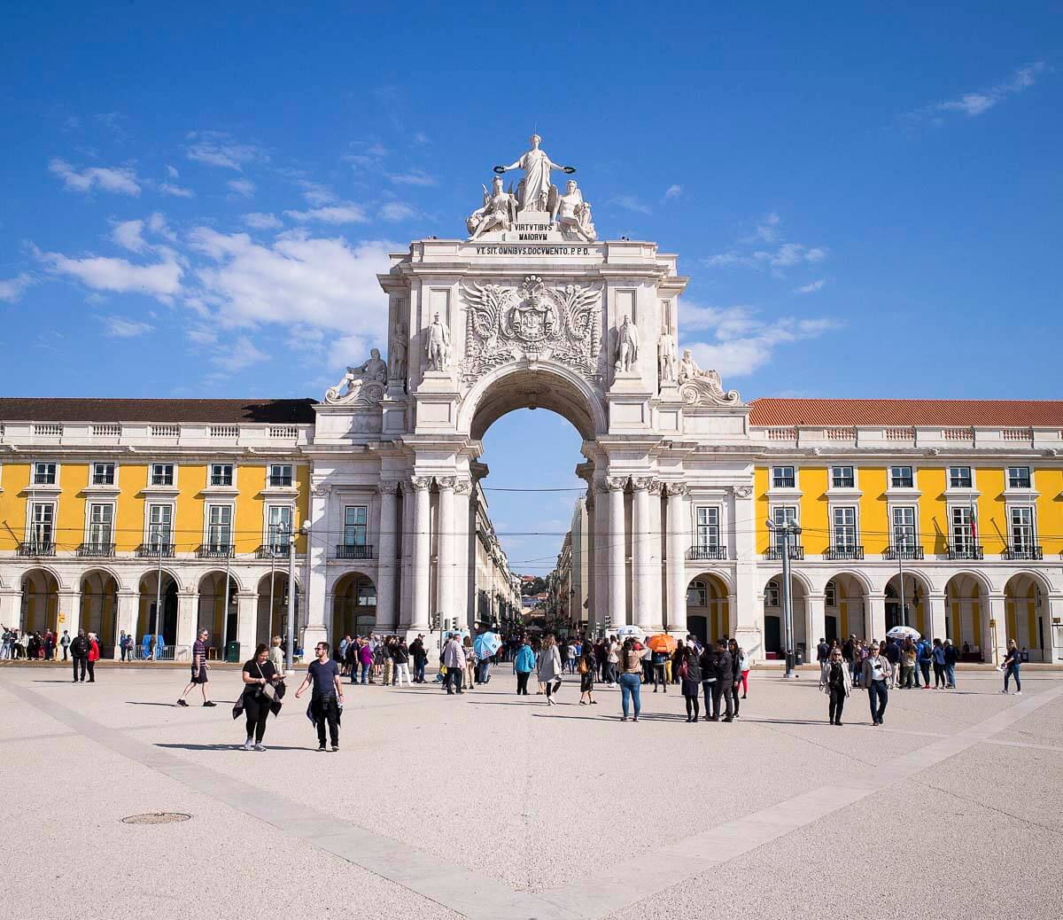 Praça do Comércio em Lisboa, com a estátua equestre de D. José I ao centro e o Arco da Rua Augusta ao fundo, sob um céu azul claro.