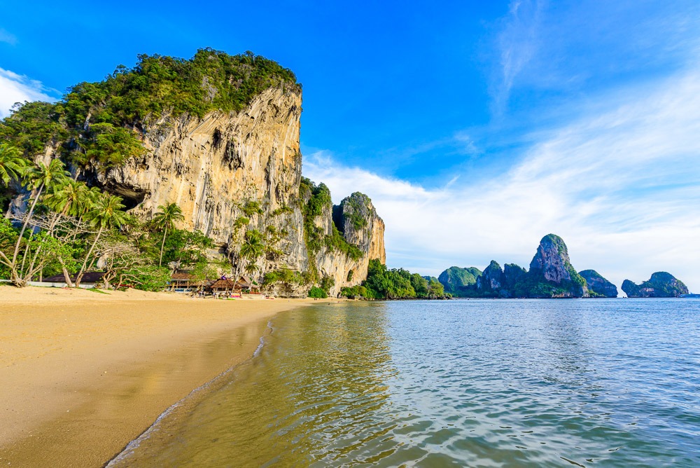 Praia de Tonsai com vegetação tropical, areia dourada e águas tranquilas, ideal para escaladores e aventureiros.