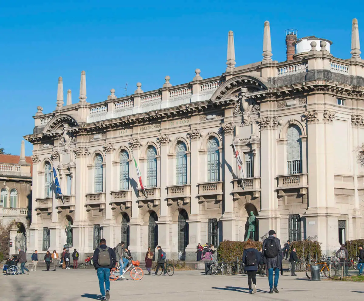 Entrada do Politecnico di Milano, com arquitetura clássica e estudantes na praça.