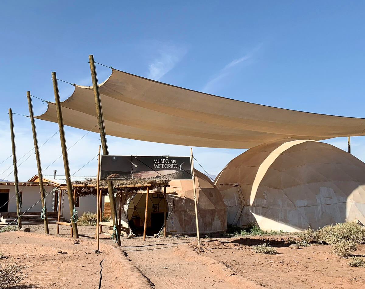 Entrada do Museo del Meteorito, em San Pedro de Atacama, com estrutura de lona e cúpulas de cor clara.