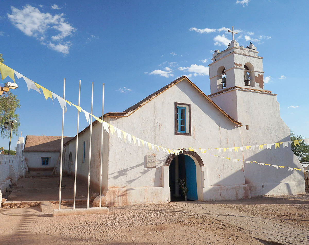 Igreja de San Pedro de Atacama com fachada branca e detalhes rústicos.