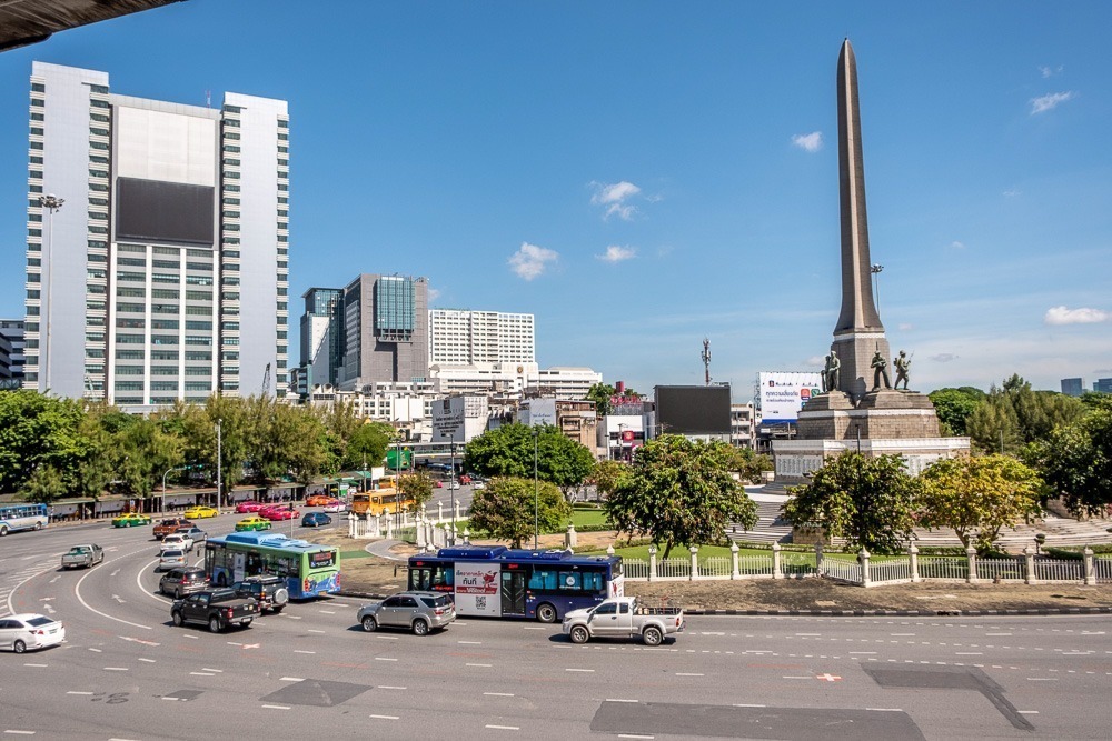 Região da rotatória ao redor do Victory Monument, com alguns carros e ônibus.
