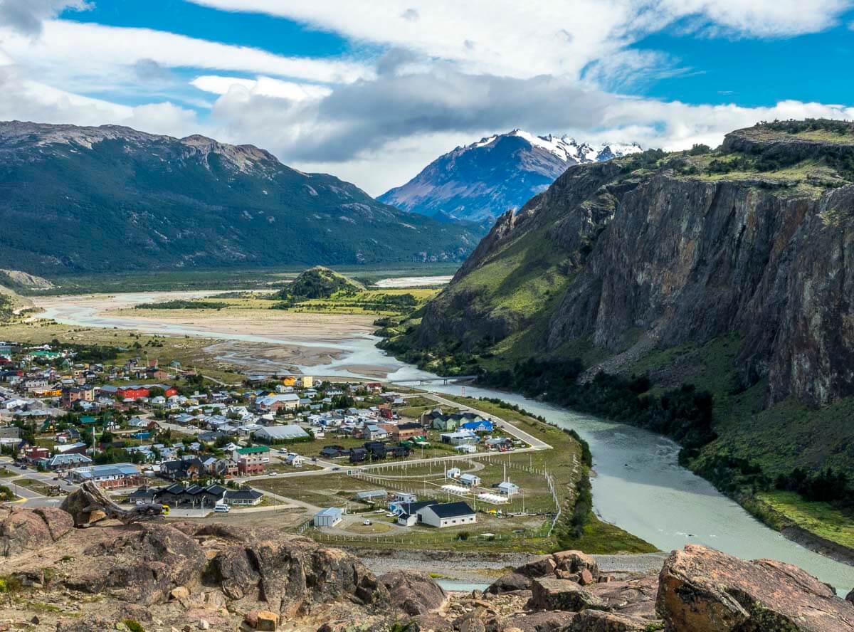 Vista aérea de El Chaltén, com casas coloridas, montanhas e um rio serpenteando pela paisagem.