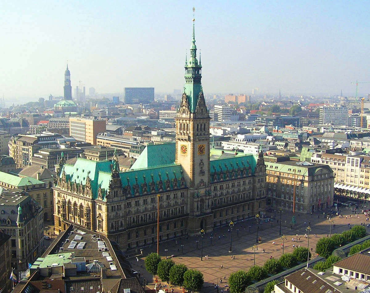 Vista aérea da prefeitura de Hamburgo no Altstadt, cercada por edifícios históricos e uma ampla praça.