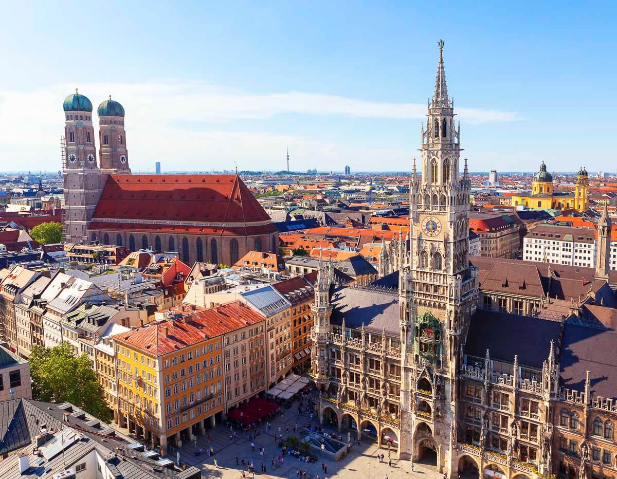 Vista aérea de Marienplatz, com a Neues Rathaus e a Frauenkirche em destaque, cercadas por edifícios históricos no centro de Munique.