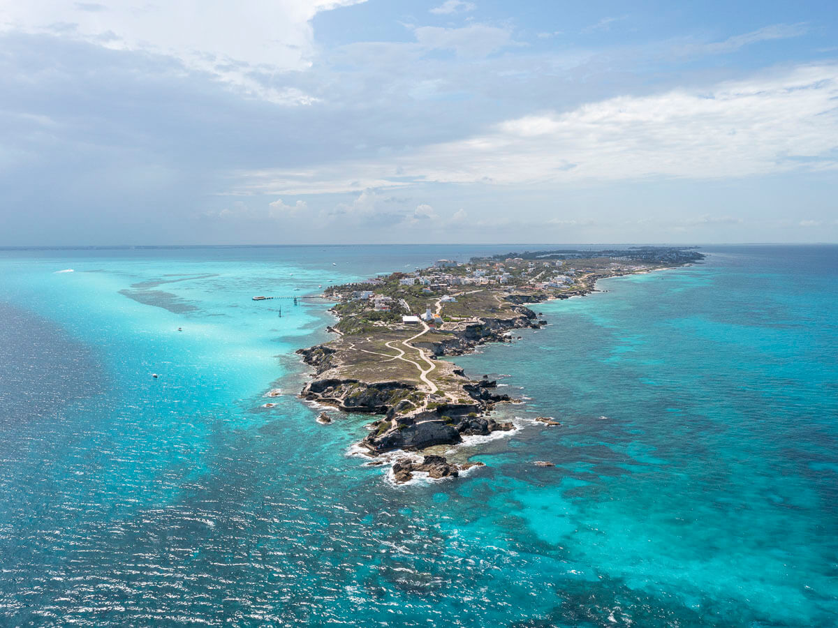 Vista aérea de Isla Mujeres, uma ilha cercada por águas azul-turquesa e recifes.