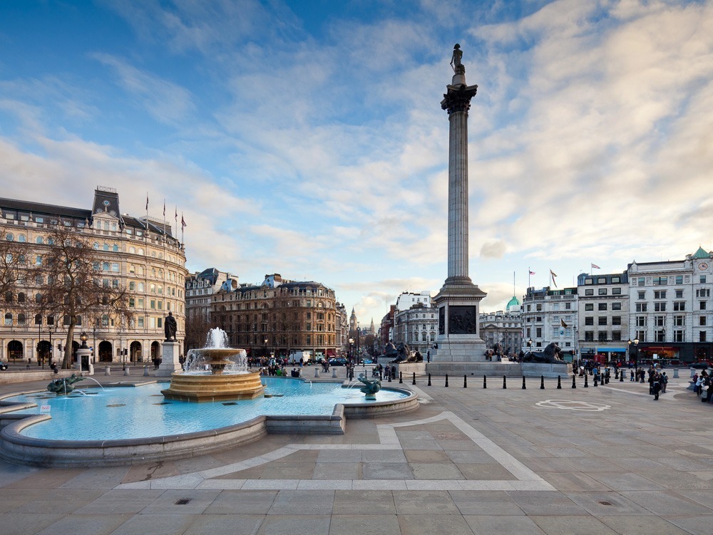 Trafalgar Square, em Londres, com a Coluna de Nelson ao centro, fontes e edifícios históricos ao fundo.