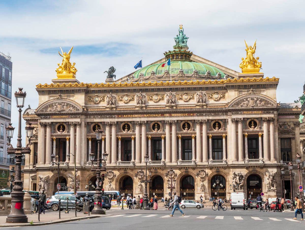 Fachada da Ópera Garnier, em Paris, com sua arquitetura imponente, esculturas douradas e uma cúpula verde.