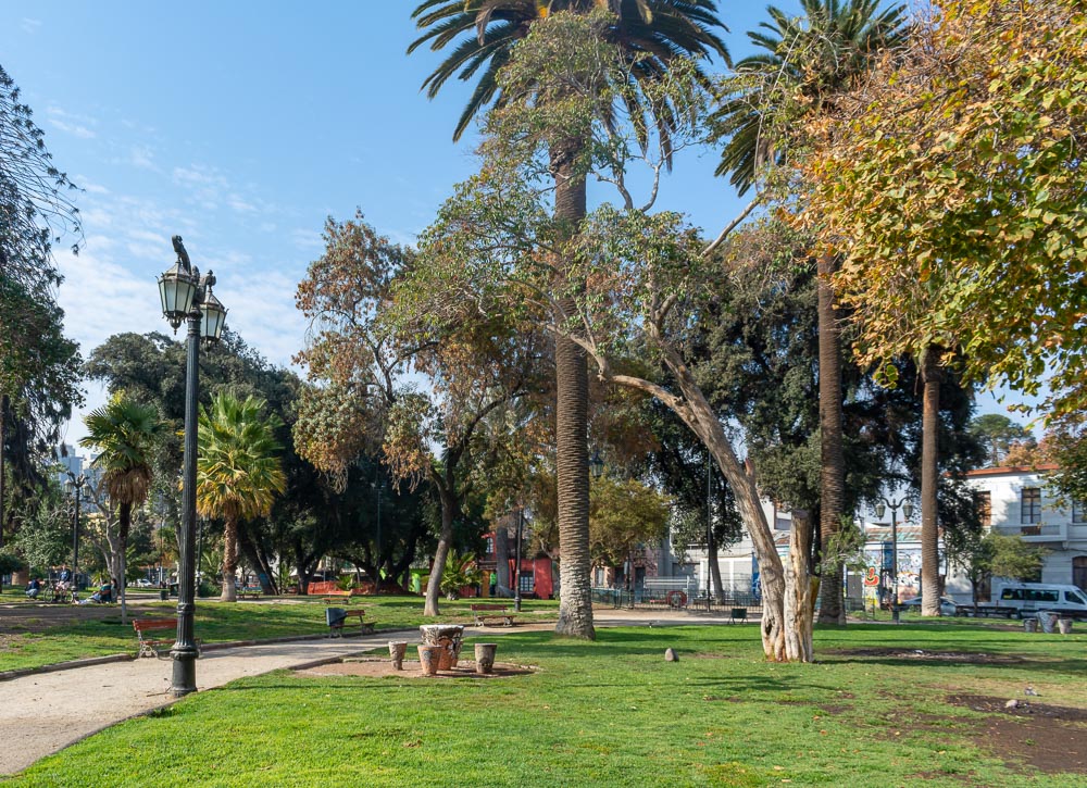 Plaza Brasil arborizada com palmeiras e bancos de madeira no bairro Brasil, em Santiago.