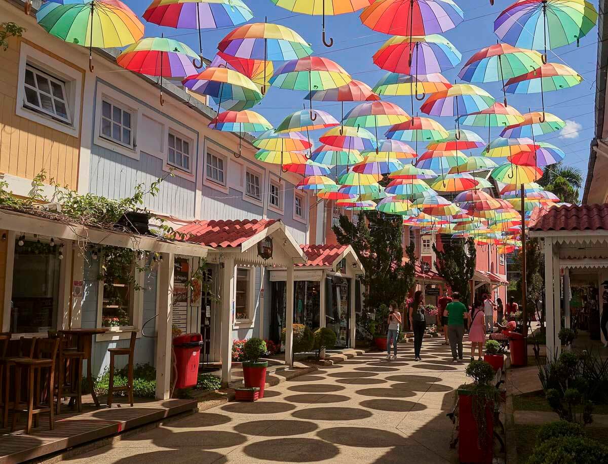 Rua charmosa no centro de Penedo, com guarda-chuvas coloridos suspensos.