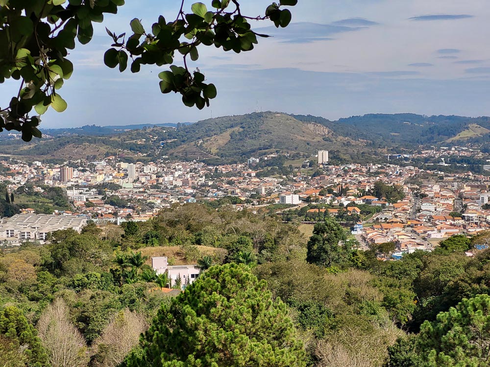 Vista aérea de São Roque com colinas verdes ao fundo, casas e prédios espalhados pela paisagem.