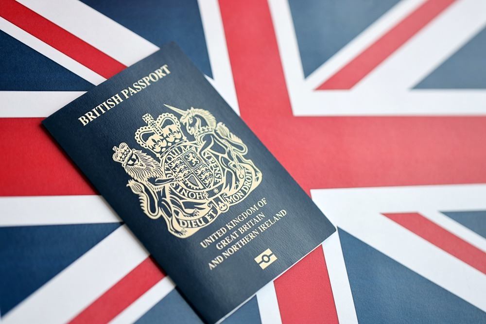 Passaporte britânico com brasão dourado sobre bandeira do Reino Unido.