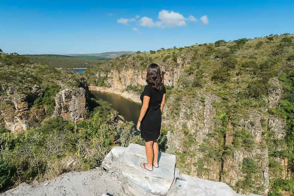 A Dri em pé sobre pedra no Mirante dos Canyons, com vista para o rio entre paredões verdes.