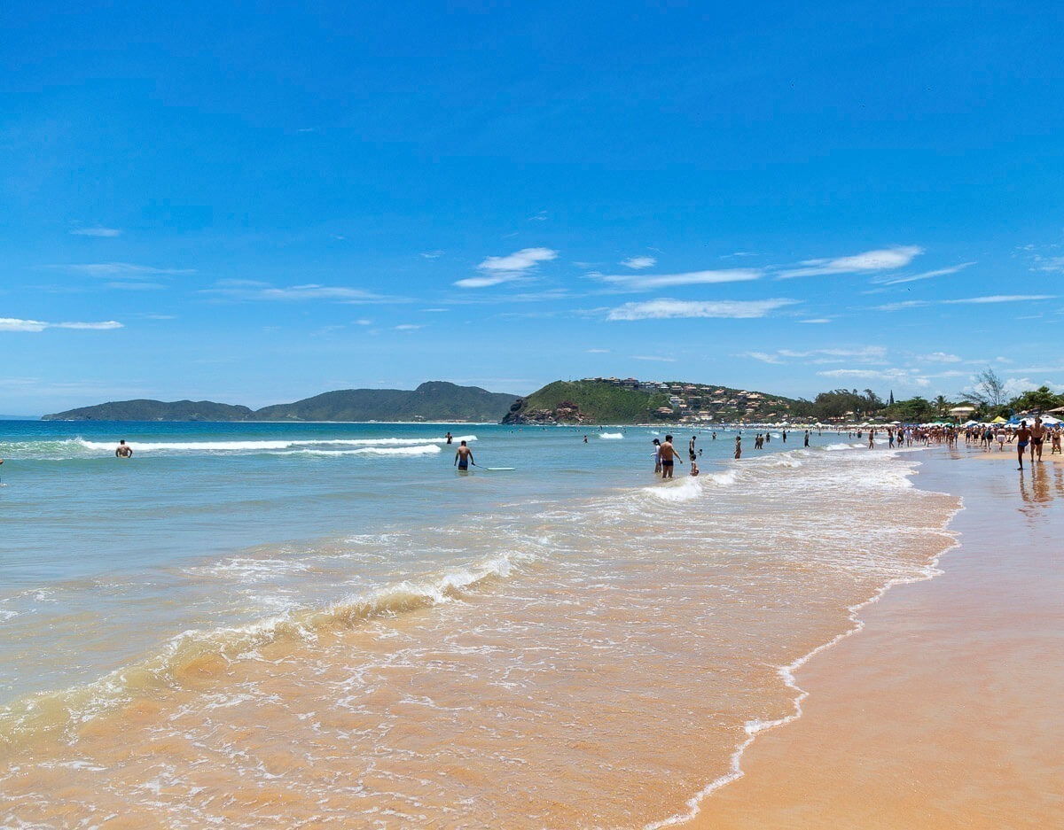 Praia de Geribá em Búzios com mar calmo, areia dourada e muitos banhistas aproveitando o sol.