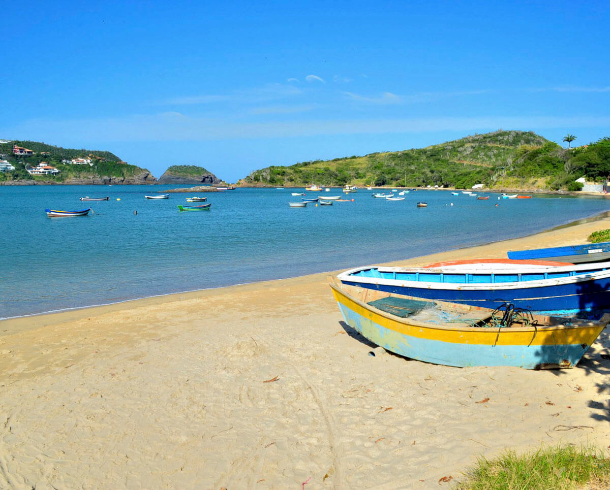 Vista da Praia da Ferradura em Búzios, com barcos no mar calmo e areia clara ao entardecer.