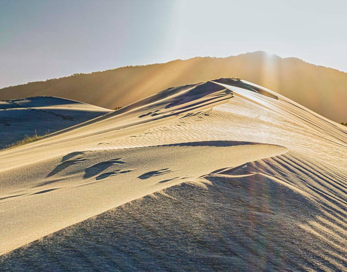Dunas do Santinho com relevo ondulado e luz dourada do entardecer iluminando a areia.