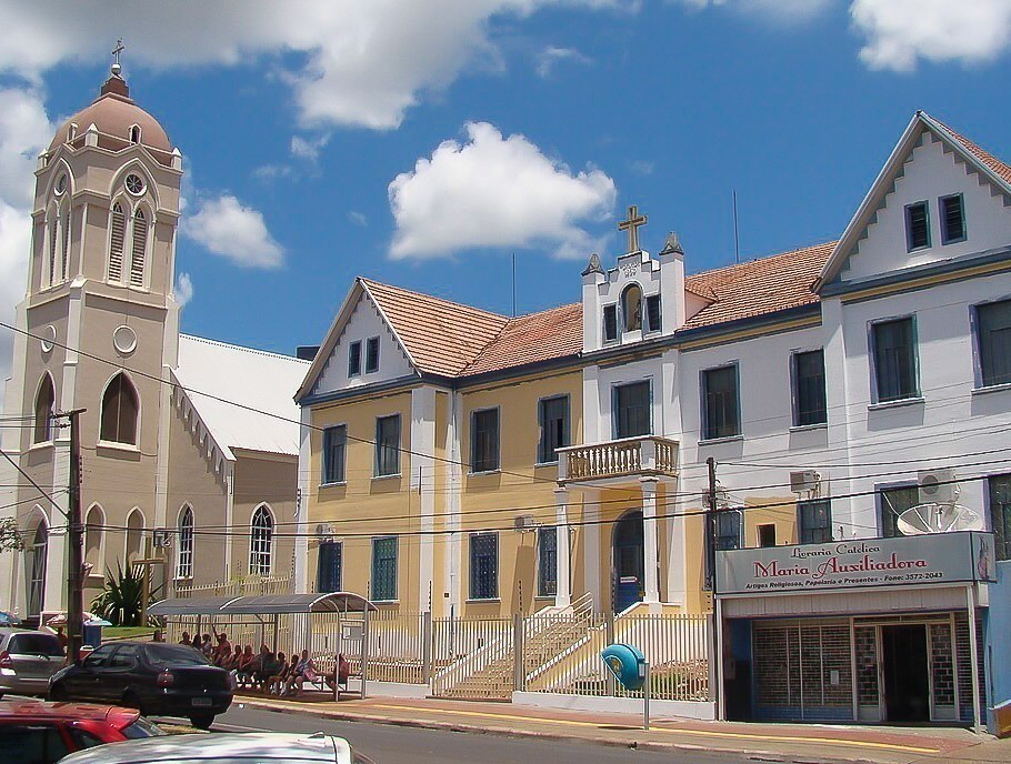 : Fachada da Paróquia São João Batista no centro de Foz do Iguaçu, com torre e prédio anexo.