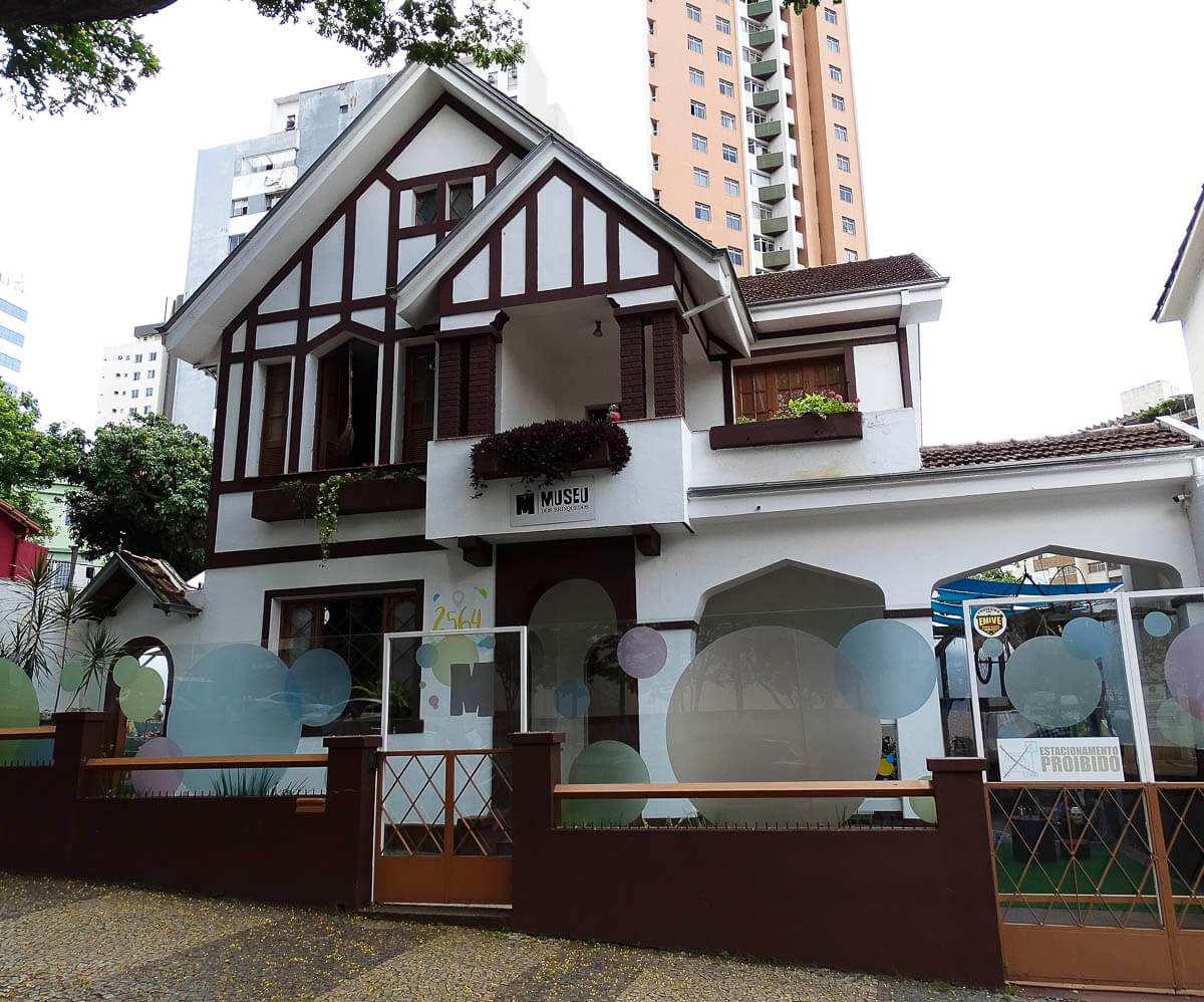 Fachada de uma casa em estilo enxaimel adaptada como museu, cercada por prédios modernos.