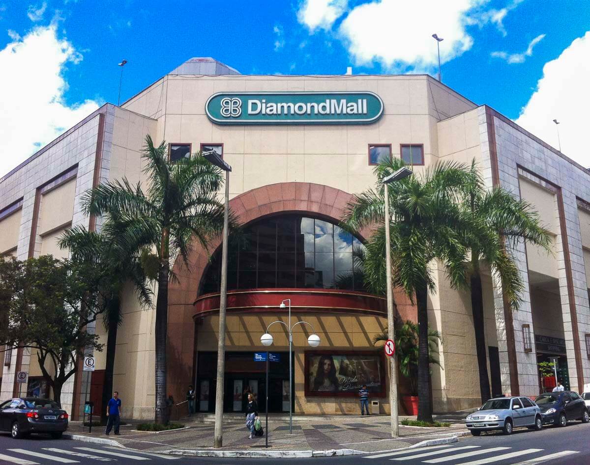 Fachada do shopping DiamondMall com palmeiras, carros estacionados e entrada principal em arco.