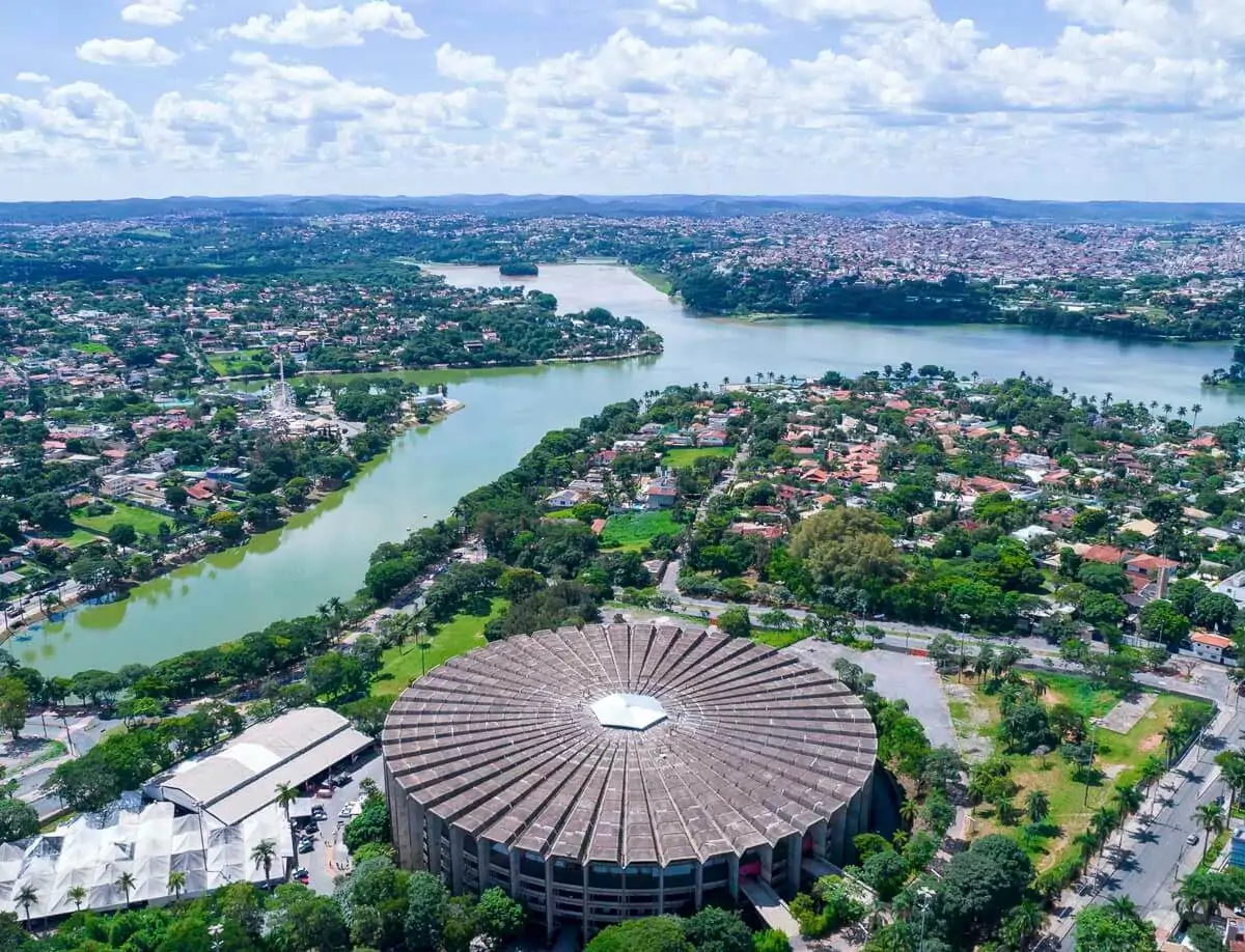 Vista aérea da Lagoa da Pampulha com o Mineirinho em destaque, cercados por casas e vegetação.