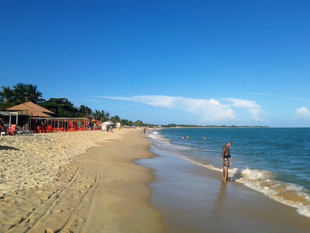 Praia de Taperapuã em Porto Seguro com mar azul, barracas de praia e banhistas na areia