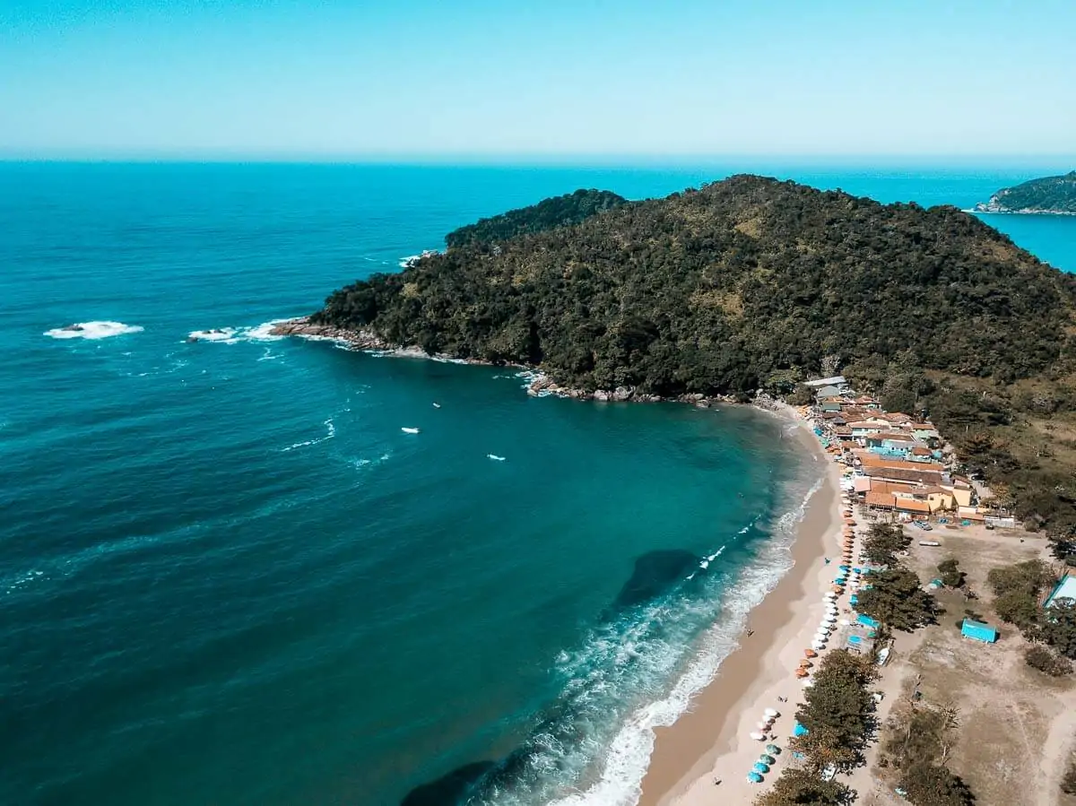 Praia dos Ranchos, em Trindade, com faixa de areia ampla, bares rústicos e mar calmo.