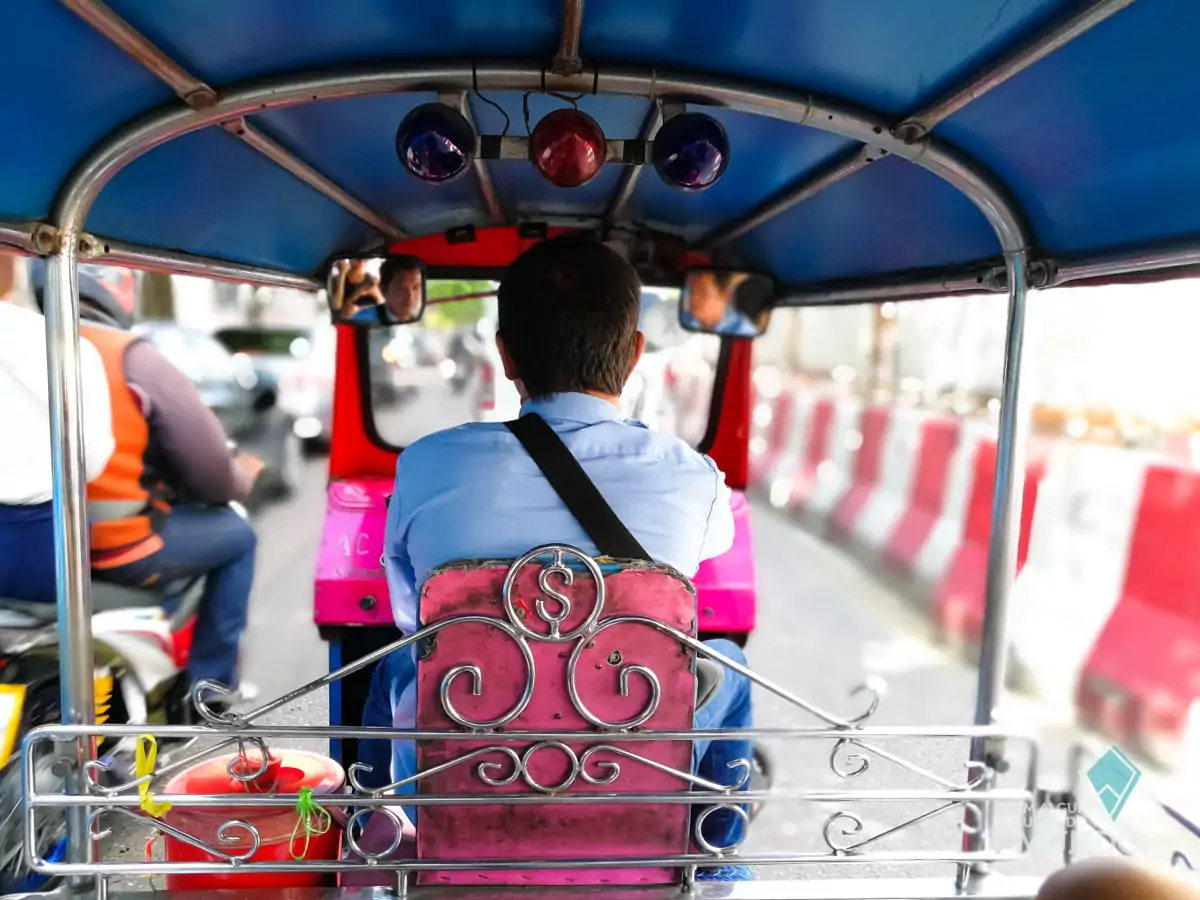 Passageiro em tuk-tuk em movimento pelas ruas movimentadas de Bangkok.
