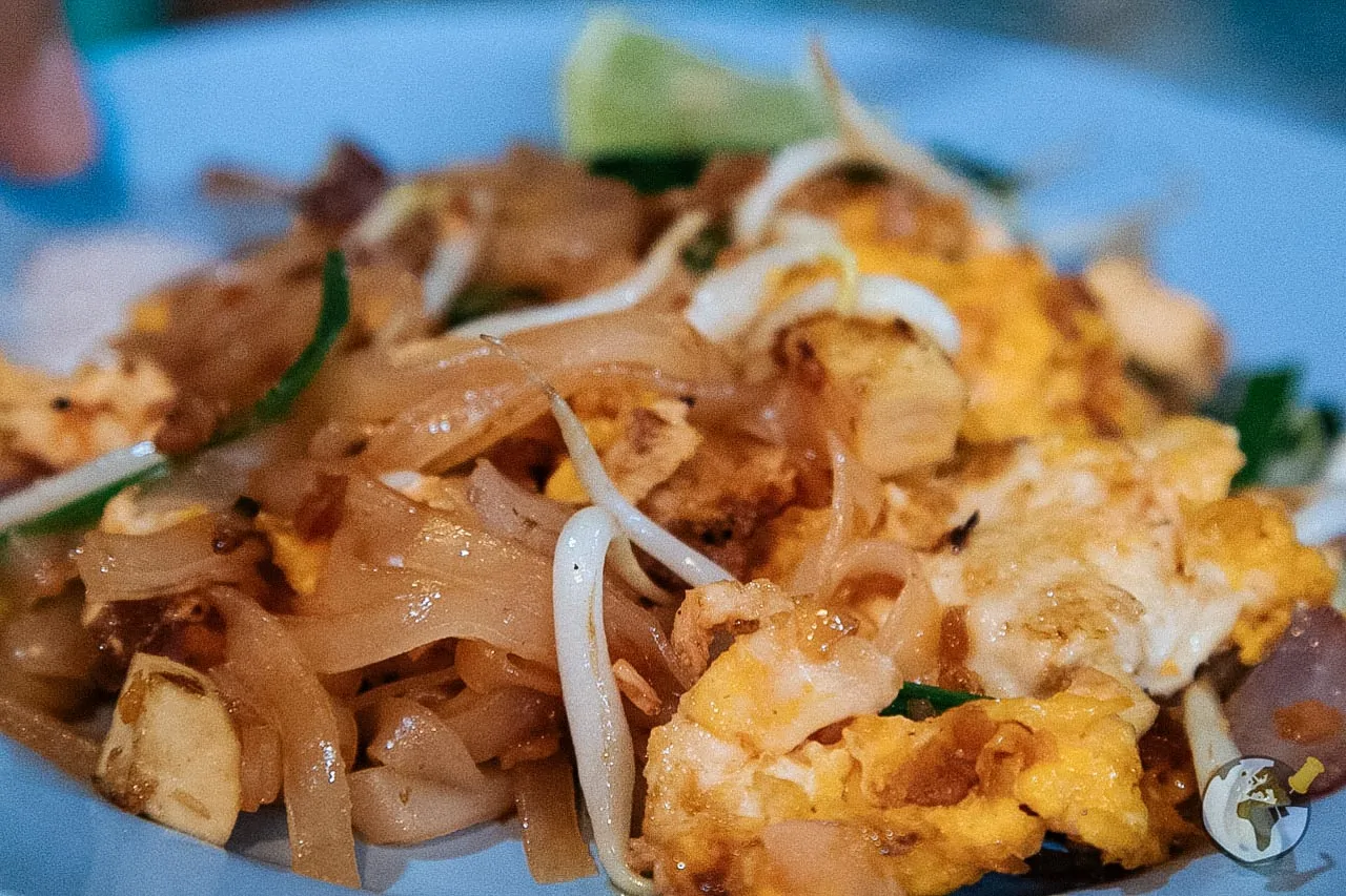 Pad thai com ovos, brotos e tofu servido em prato azul.