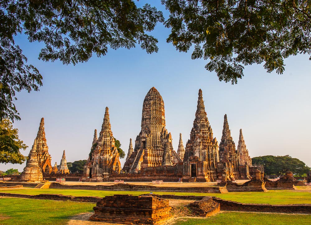 Complexo de templos antigos em Ayutthaya com torres simétricas sob céu claro.