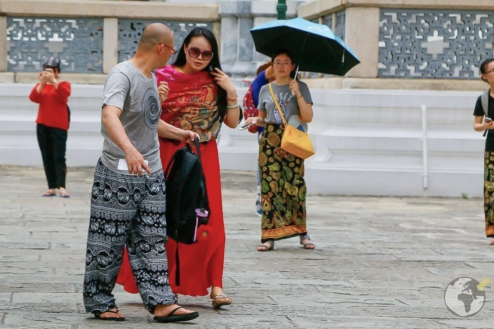Visitantes usando calças e saias cobrindo as pernas em frente ao Grande Palácio de Bangkok