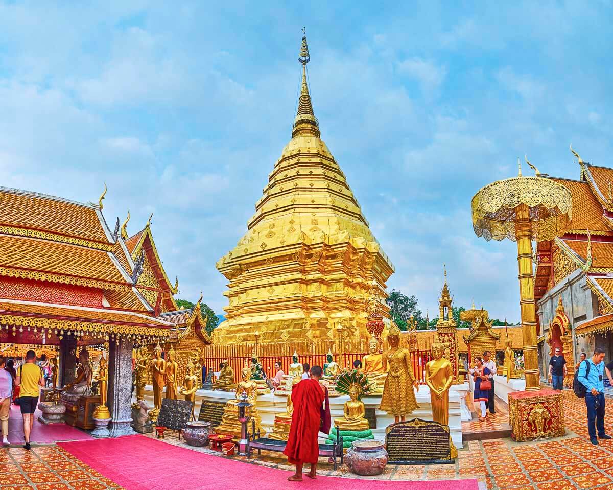 Templo Wat Phra That Doi Suthep com estupa dourada rodeada por fiéis e monges.