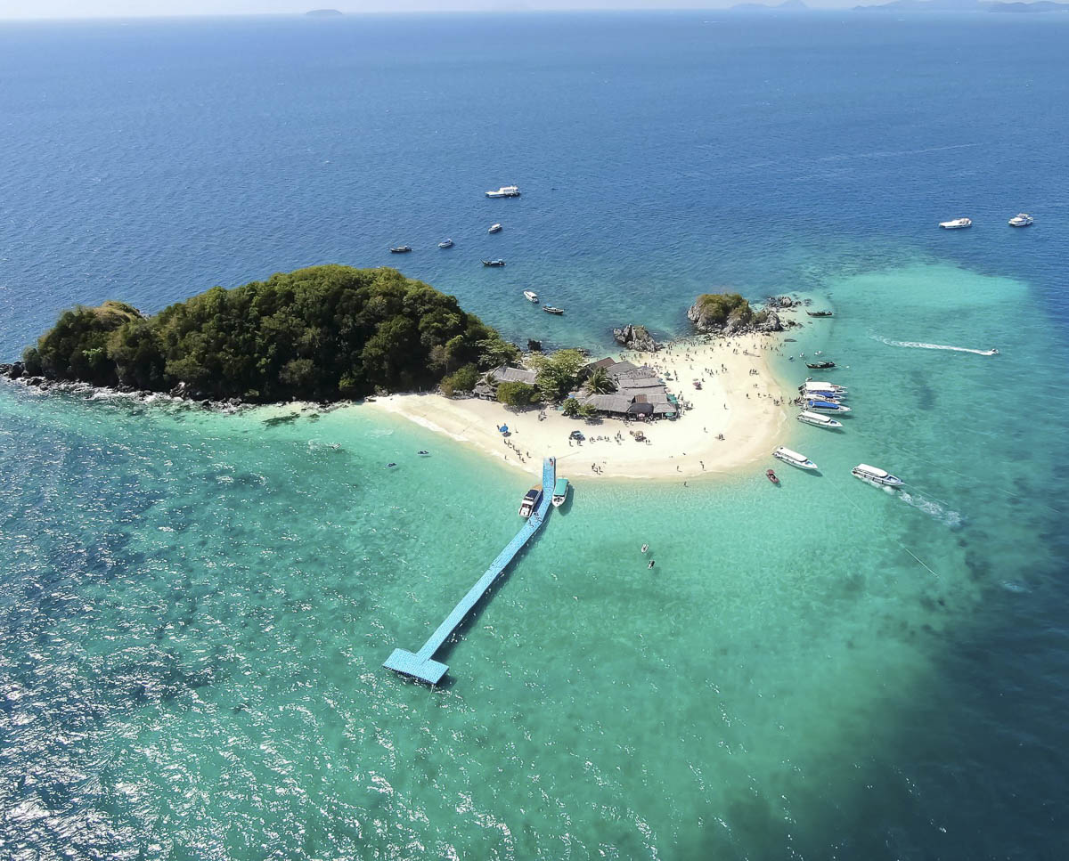 Vista aérea da Ilha Khai Nai, em Phuket, com areia branca, mar azul-turquesa e pier flutuante cercado por lanchas.