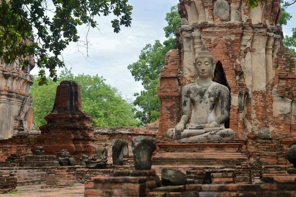 Estátua de Buda sentada rodeada por ruínas no Wat Phra Mahathat.
