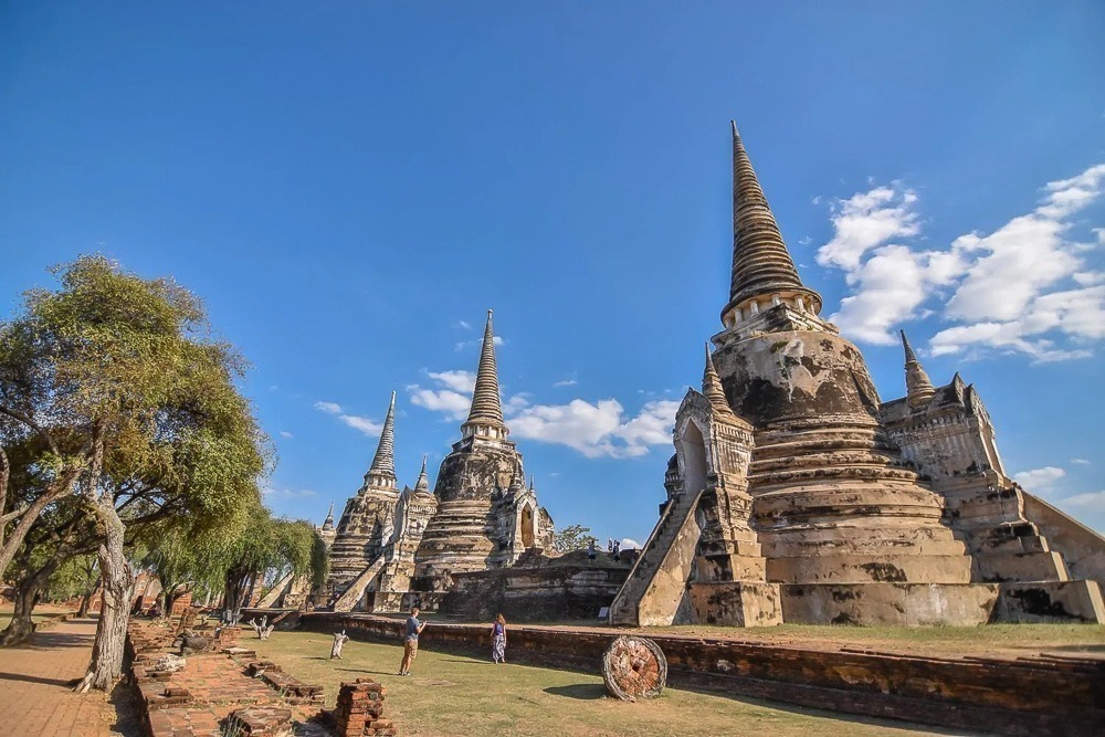Três chedis alinhados em Wat Phra Si Sanphet sob céu azul.
