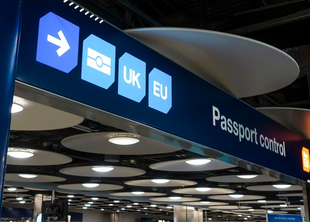 Sinalização de controle de passaporte no aeroporto, com ícones indicando entrada para passaportes da UE, Reino Unido e outros.