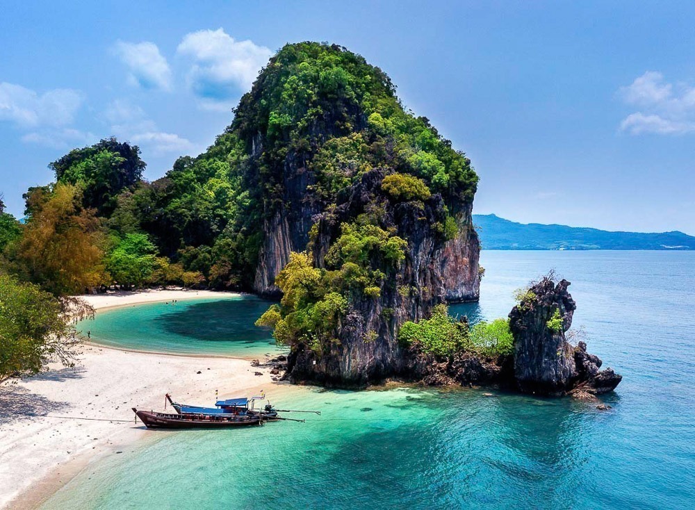 Ilha Koh Hong vista de cima, com praia de areia branca, mar azul-turquesa e vegetação exuberante.