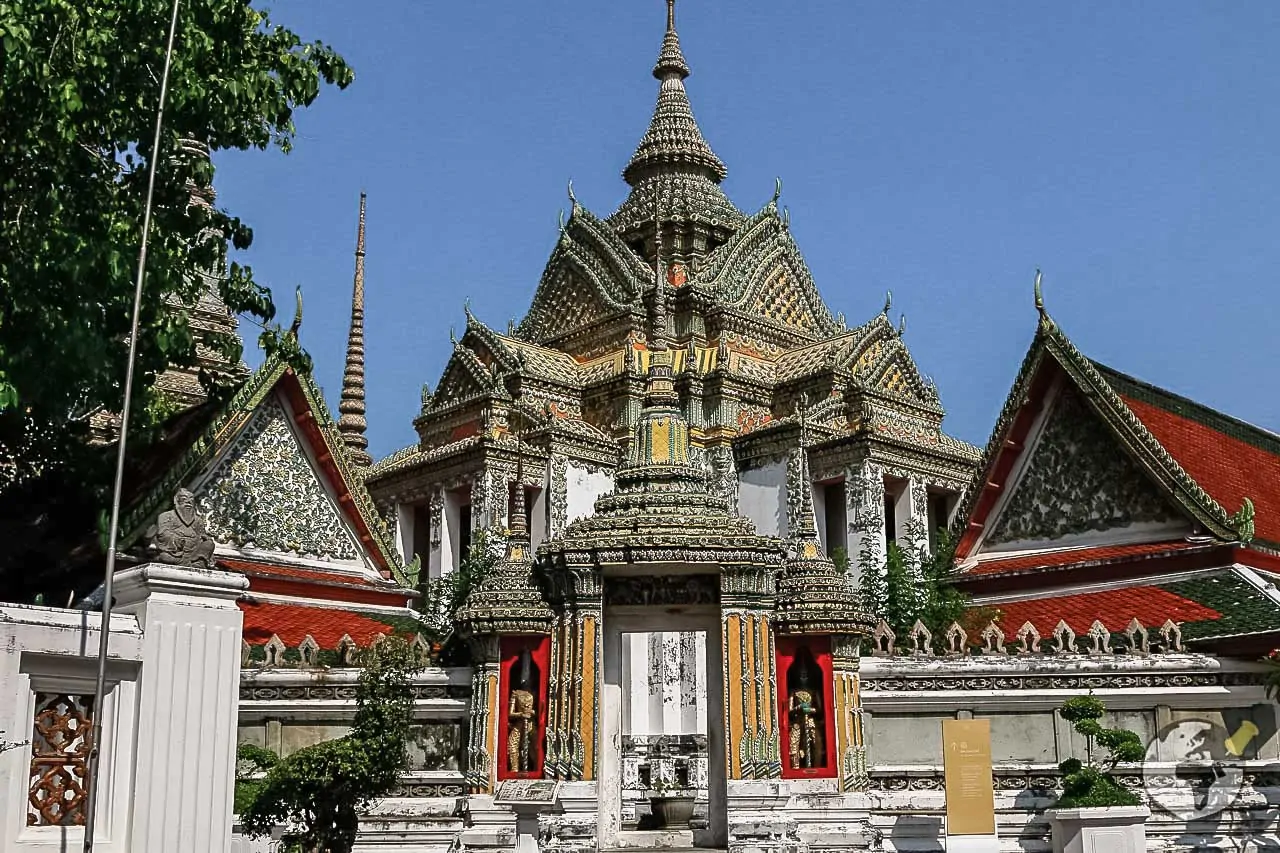 Entrada ornamentada do templo Wat Pho com telhados tradicionais tailandeses e torres decoradas.