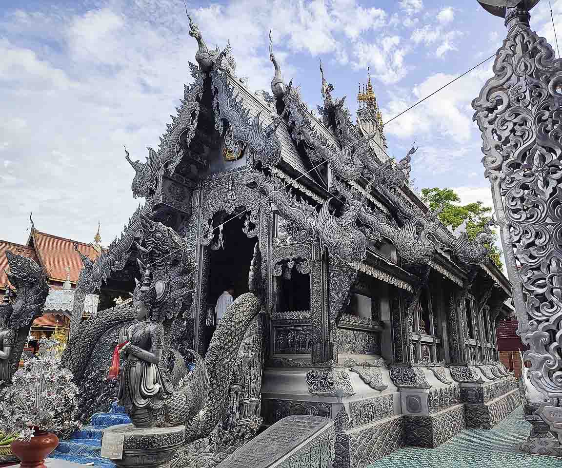 Fachada detalhada do Wat Sri Suphan, o Templo de Prata de Chiang Mai, com esculturas em relevo por toda a estrutura.
