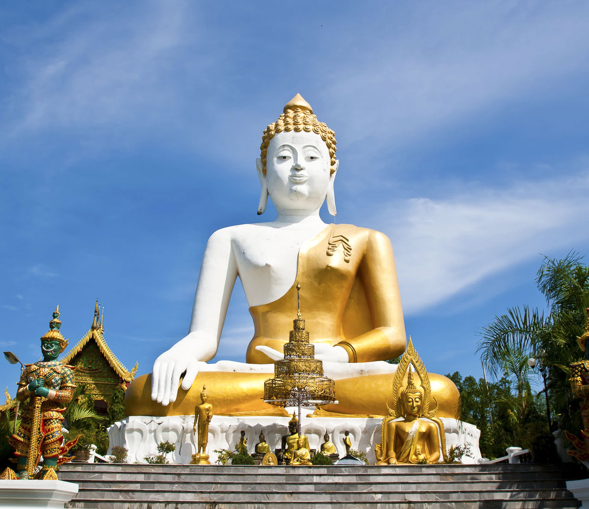 Grande estátua de Buda branco e dourado sentado em posição de meditação no templo Wat Phra That Doi Kham.