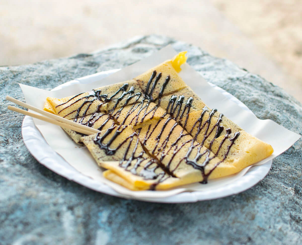 Prato de roti tailandês com cobertura de chocolate servido sobre papel.